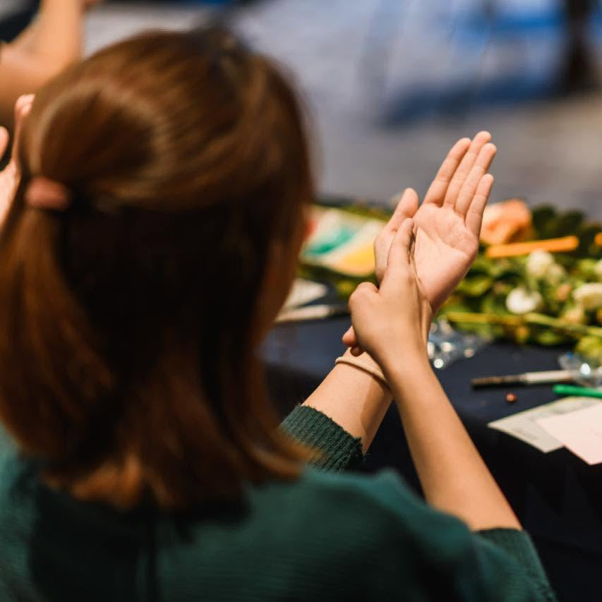 Person doing sign language with a table and floral decorations in the background