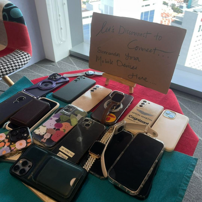 Collection of phone cases on a table with a sign in front of a window with a city view.
