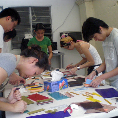 Group of people working on a craft project in a classroom setting.