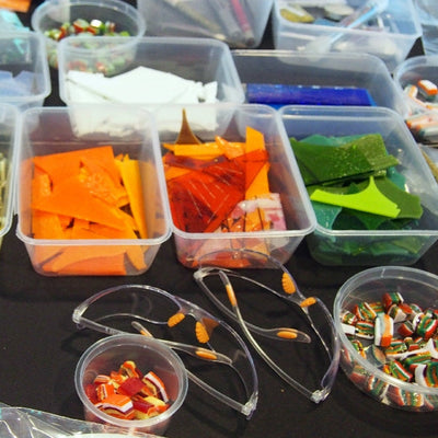 Assorted recycled glass pieces in small containers on a table